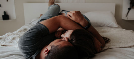 couple se faisant un câlin dans un lit
